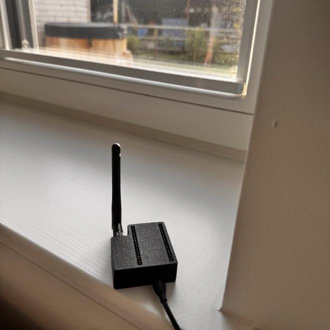 a photo of the ESPHome device in its 3D printed case, with the hot tub visible through the window in the background