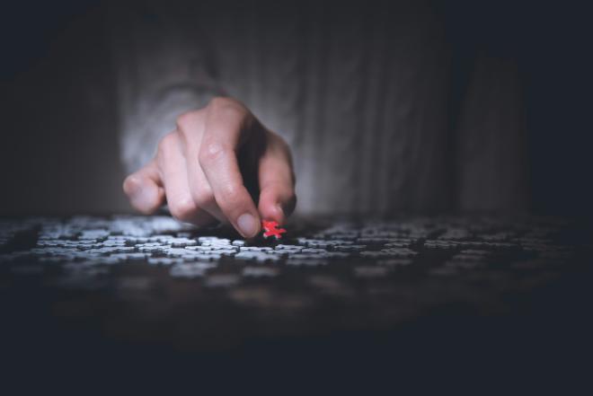 A hand finding the "missing piece" in a puzzle.
