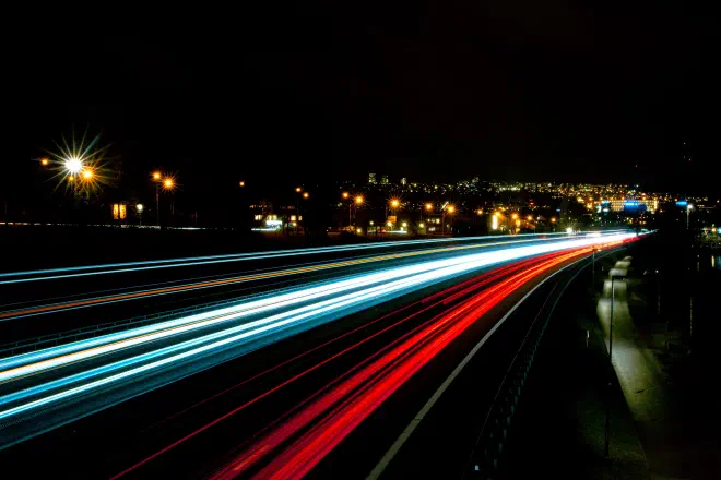A night time, time lapse scene of a busy, fast road.
